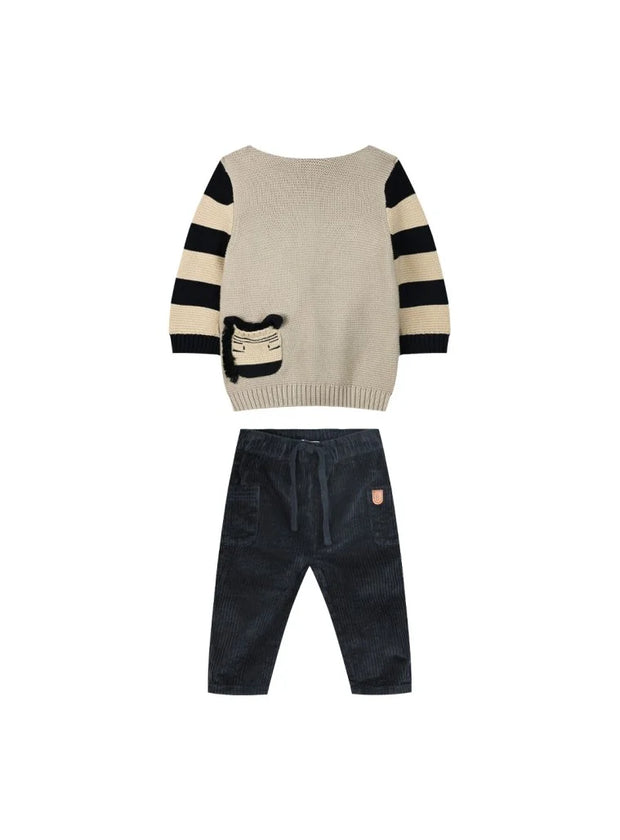 "Σετ βρεφικής ένδυσης με πλεκτή μπλούζα σε μπεζ χρώμα με ριγέ μανίκια σε μαύρο και τσέπη με σχέδιο ζωάκι, συνδυασμένη με μαύρο παντελόνι κοτλέ με λάστιχο στη μέση για άνεση. Ιδανικό για κομψές καθημερινές εμφανίσεις."