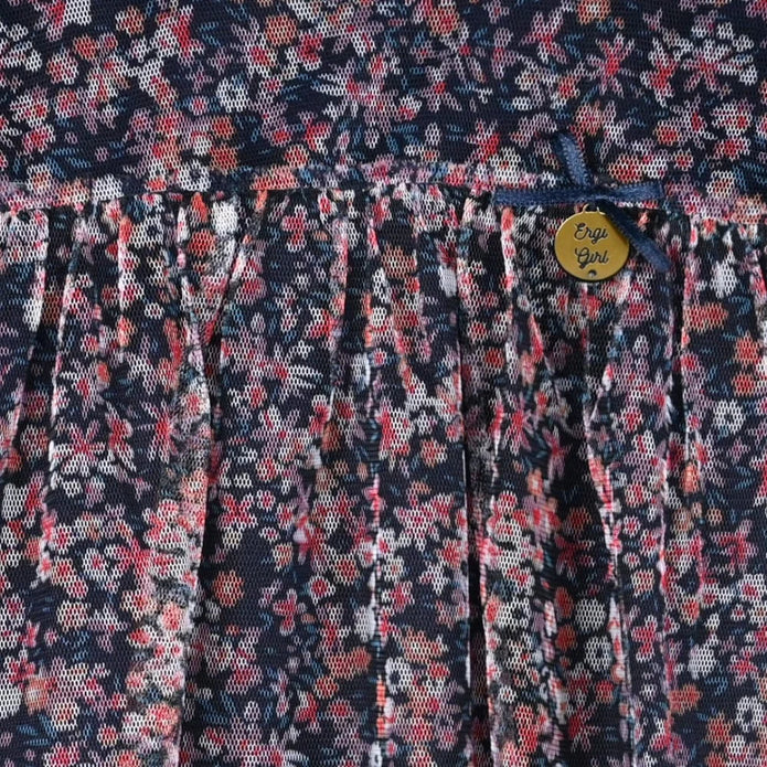 Κοριτσίστικη μπλούζα με μακριά μανίκια σε σκούρο μπλε χρώμα, διακοσμημένη με λουλουδάτο μοτίβο σε αποχρώσεις του ροζ και του λευκού. Διαθέτει διακριτικά βολάν στους ώμους και κουμπάκι για κλείσιμο στο πίσω μέρος, προσφέροντας ρομαντικό και κομψό στυλ φλοραλ πουκαμίσα για κορίτσι 