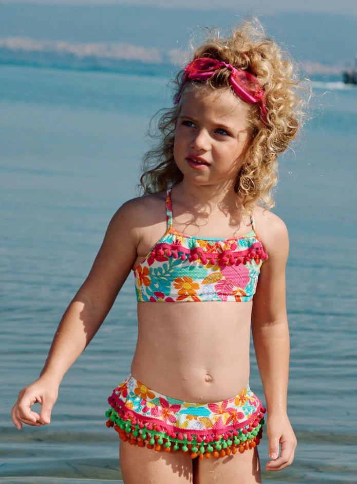 Crop top του παιδικού μαγιό μπικίνι Swimmy με πομ πομ και τροπικό μοτίβο

Πίσω όψη του σετ μαγιό μπικίνι Swimmy με χιαστί τιράντες και floral σλιπ

Παιδικό μαγιό μπικίνι Swimmy με πομ πομ και έντονα χρώματα

Κορίτσι φοράει το παιδικό μαγιό μπικίνι Swimmy στην παραλία
